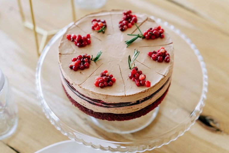 Chocolate dessert layered with cream, decorated with berries on a cake stand.