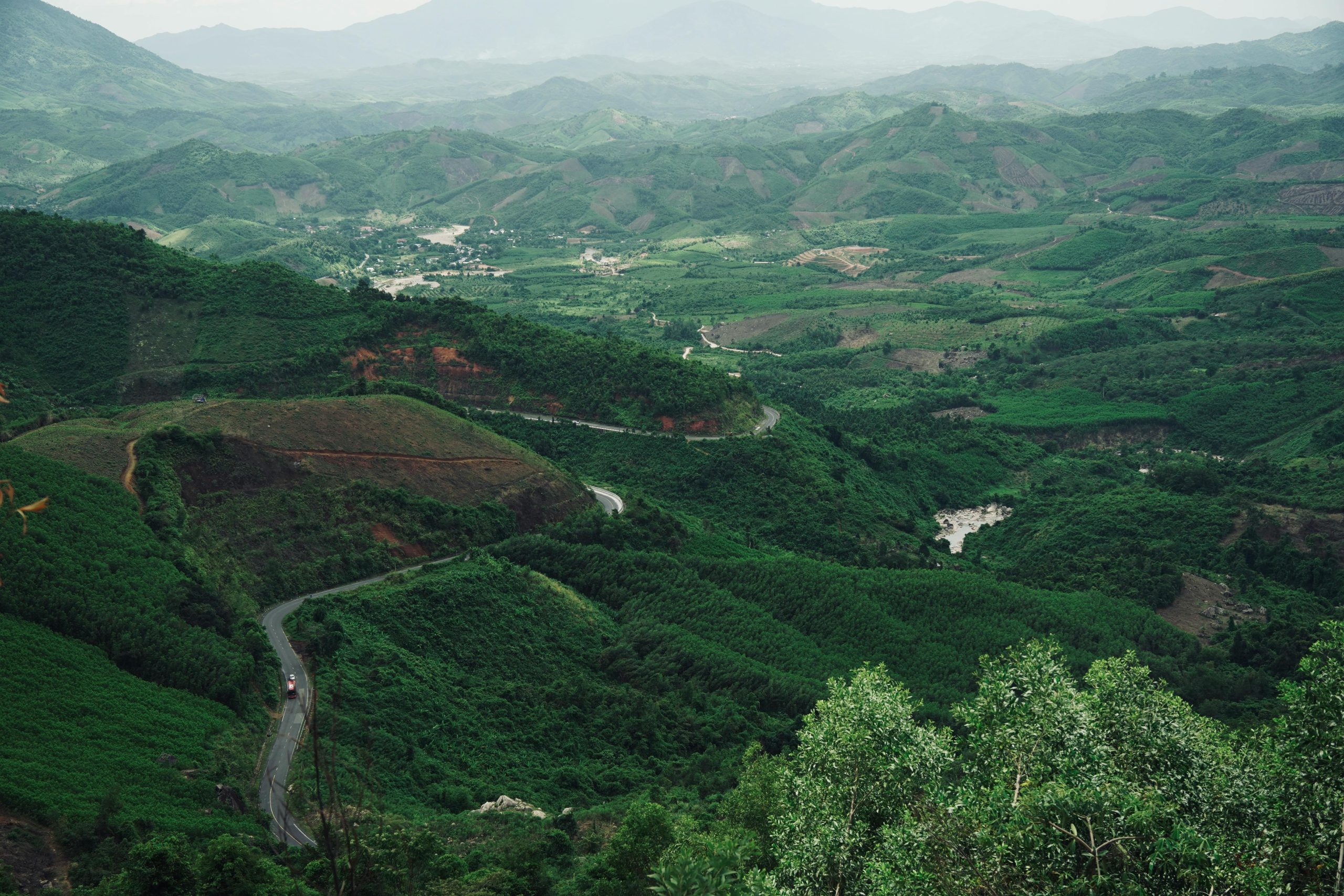 A breathtaking view of lush green hills and valleys with a meandering road creating a scenic landscape.