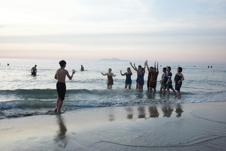 A joyful group of friends plays on the beach in Da Nang, Vietnam as the sun sets.